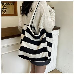 Detail van een grote zwart-wit gestreepte canvas shopper gedragen over de schouder