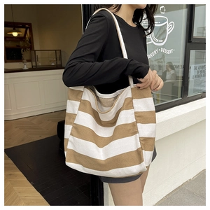 Detailoverzicht van gestreepte canvas draagtas met bruin en beige schouderriem