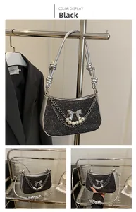 Detail of glitter black crescent bag featuring silver bow, pearls and dual chain straps