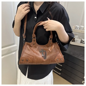 Detail of vintage brown leather handbag with metallic rivets and gothic cross pendant