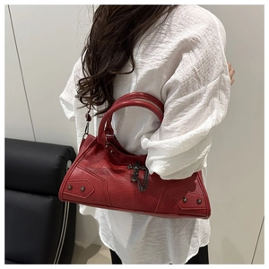Detail of red leather motorcycle bag featuring metallic rivets and silver cross charm