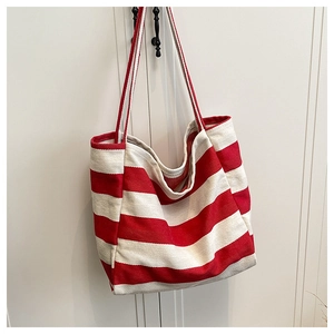 Detail van rood-wit gestreepte canvas shopper hangend aan een zwarte metalen haak