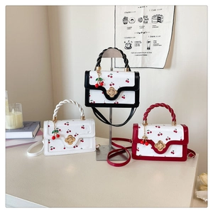 Vue détaillée de trois sacs à main aux motifs cerises avec fermoirs fleurs dorées