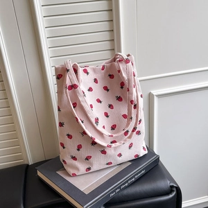 Dettaglio della borsa tote in velluto a coste rosa con motivo a fragole rosse e trama morbida