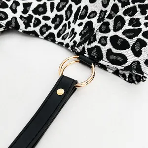 Detail of leopard print fabric with golden ring hardware and black leather strap