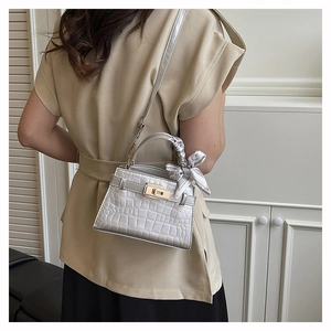 Detail of silver crocodile pattern mini handbag with gold lock and silk scarf handle wrap