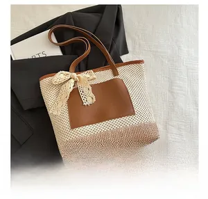 Detail of the woven straw tote bag featuring a lace bow and brown faux leather trim