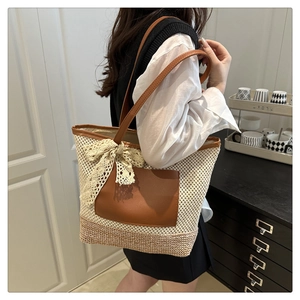Detail of hand-woven straw tote bag with brown leather pocket and delicate lace bow