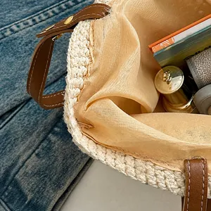 Nahaufnahme der gewebten Strandtasche aus Stroh mit Ledergriffen und geräumigem Futter