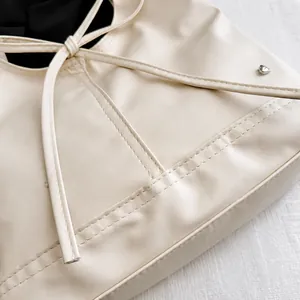 Dettaglio della borsa in pelle color crema con borchia a cuore argento e cuciture rifinite