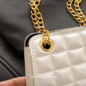 Close-up of golden metal eyelet and chain strap on cream quilted leather crossbody bag