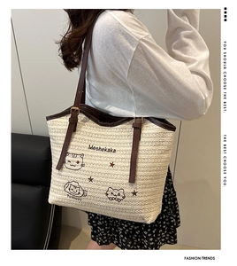 Détail d'un sac cabas en paille avec broderie chat et poignées en cuir pour un style estival