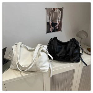 Vue détaillée de grands sacs cabas en cuir noir et blanc sur une étagère minimaliste