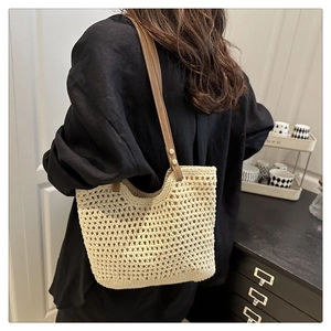 Detalle del bolso tote beige tejido con correas de cuero marrón y remaches de metal dorado