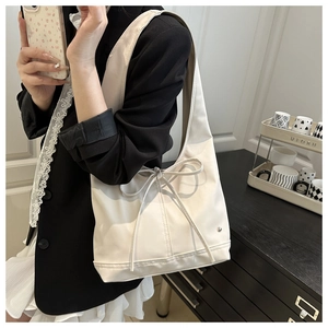 Dettaglio elegante borsa tote in ecopelle crema con fiocco e tracolla larga
