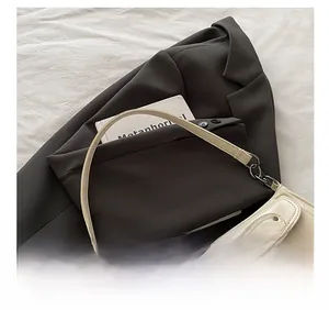 Détail de la bandoulière confortable et du cuir crème lisse du sac sous le bras de luxe