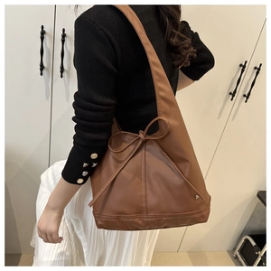 Borsa tote in pelle cerata marrone con fiocco, indossata a spalla da una modella
