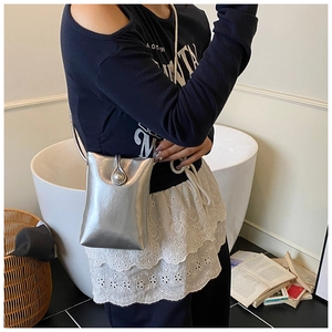 Detalle de mini bolso plateado para móvil con cierre de perla elegante y correa fina