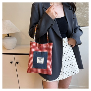 Detail of red checkered canvas tote with denim pocket and colorful braided rope handles