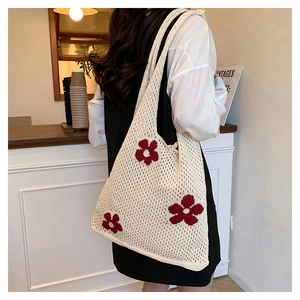 Detailaufnahme der elfenbeinfarbenen Häkeltasche mit leuchtend roten Blumenmustern
