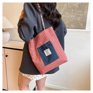 Detailed view of red checkered canvas tote bag with denim pocket and woven rope handles