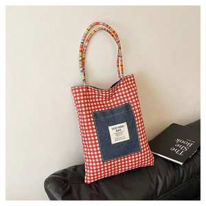 Détail du cabas en toile à carreaux rouges avec poignées tressées et poche en denim