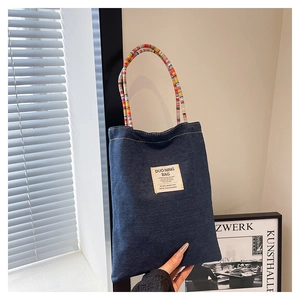 Détail d'un sac cabas en denim avec étiquette de marque et anses tissées colorées