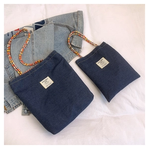 Détail du sac cabas en denim avec écusson vintage et poignée en perles colorées