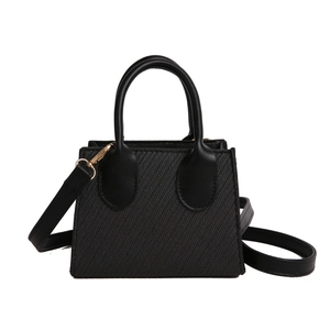 Minimalist black trapezoid handbag with textured woven finish and adjustable crossbody strap