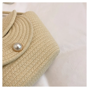 Dettaglio borsa a secchiello intrecciata beige con fibbia elegante in maxi perla