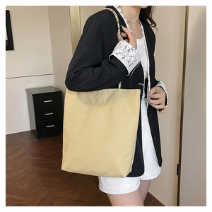 Close-up of beige canvas tote bag with gold lettering and colorful woven shoulder strap