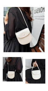 Detail of off-white saddle bag featuring a round buckle and adjustable strap on a model