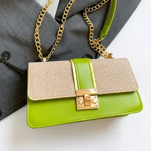 Détail du sac bandoulière avec rabat en paille, cuir vert et bandoulière chaîne dorée