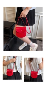 Detail view of the bright red saddle bag showing smooth PU leather texture and flap closure