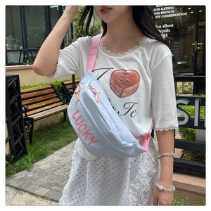 Close-up of light blue nylon chest bag with pink Lucky lettering and adjustable strap