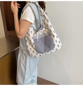 Detail of canvas tote bag featuring blue ribbon patterns and a lace-trimmed plaid pocket