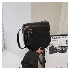 Close-up of black saddle bag with glossy finish, metal buckle, and adjustable strap