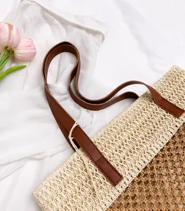 Detail van beige strooien handtas met bruine lederen handvatten en fijn stikwerk
