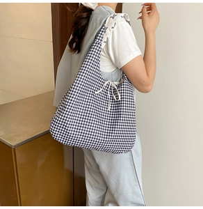 Detail of checkered canvas tote bag featuring a white drawstring bow and bunny print strap