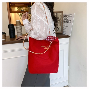 Dettaglio della borsa tote in tela rossa con manico di perline colorate e fodera a quadretti
