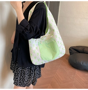 Floral canvas tote with green gingham pocket and lace trim shown in use on shoulder
