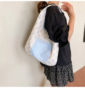 Detail of floral canvas tote bag featuring blue bow print and lace-edged plaid pocket