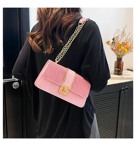 Détail du sac à chaîne en tweed rose avec fermoir doré porté par un mannequin en extérieur