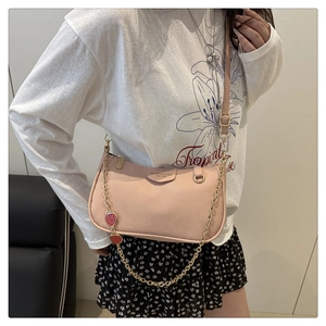 Detailed view of pink lychee leather bag with golden chain and cute strawberry charms
