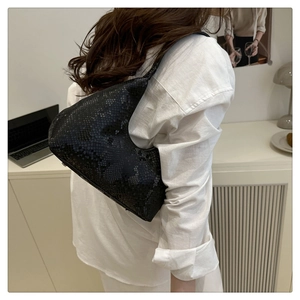 Dettaglio della borsa hobo nera con motivo a serpente indossata da modella in interno