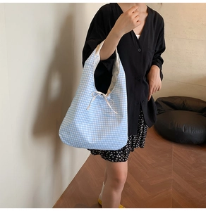 Detail of blue gingham canvas tote bag with floral lining and drawstring bow tie