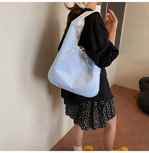 Detail of blue and white checkered canvas tote bag with a decorative bow on the handle