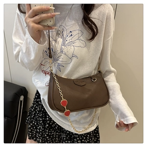 Close-up of brown litchi pattern leather bag with chain strap and strawberry charms