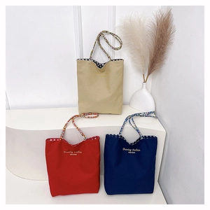 Detailed view of canvas tote bags in beige red and blue with plaid pattern straps