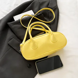 Detail view of a bright yellow Boston bag placed on a grey blazer and white sheets